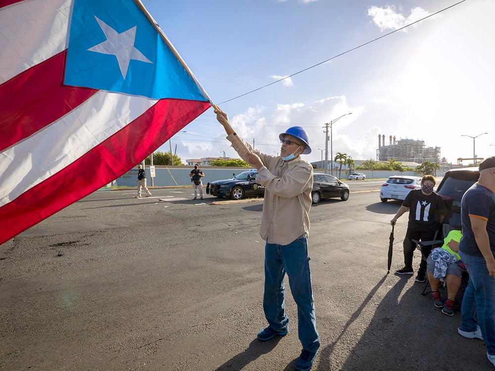 Un manifestante ondea la bandera puertorriqueña durante una protesta pública contra la privatización del servicio de energía eléctrica en San Juan, Puerto Rico, en junio de 2021.