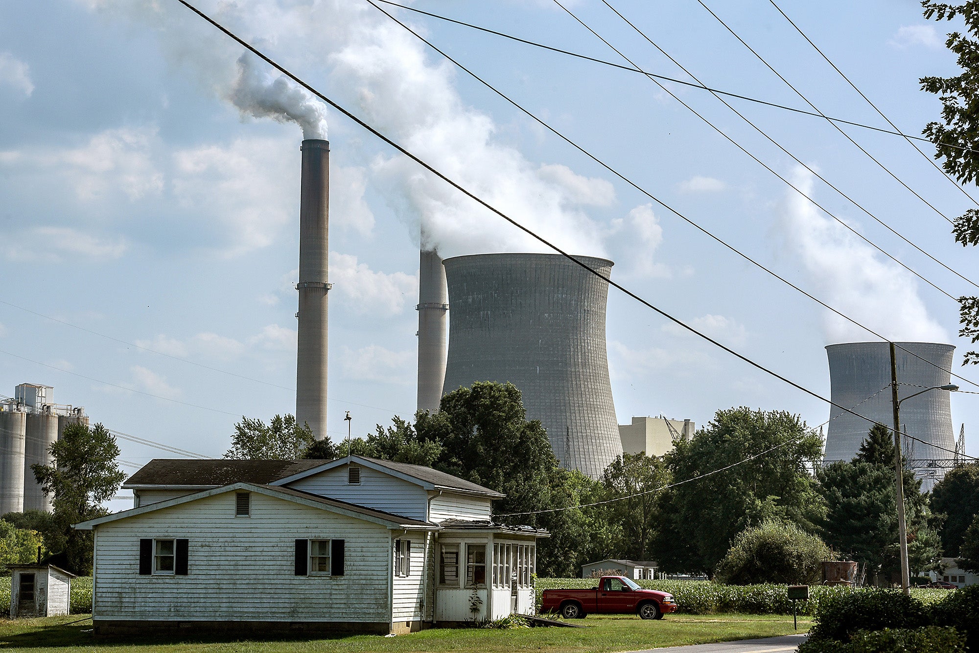 A farm house in the foreground with a large coal plant looming behind it.